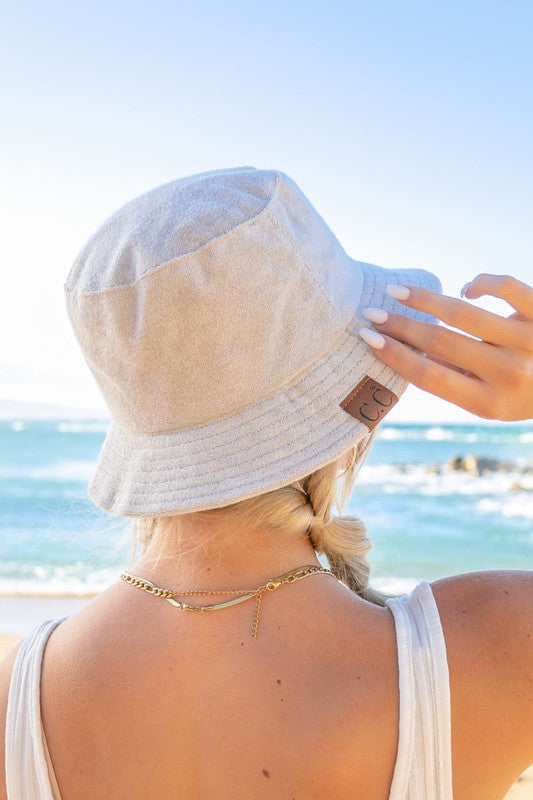 Woman wearing a CC Terry Cloth Bucket Hat and sunglasses at the beach.