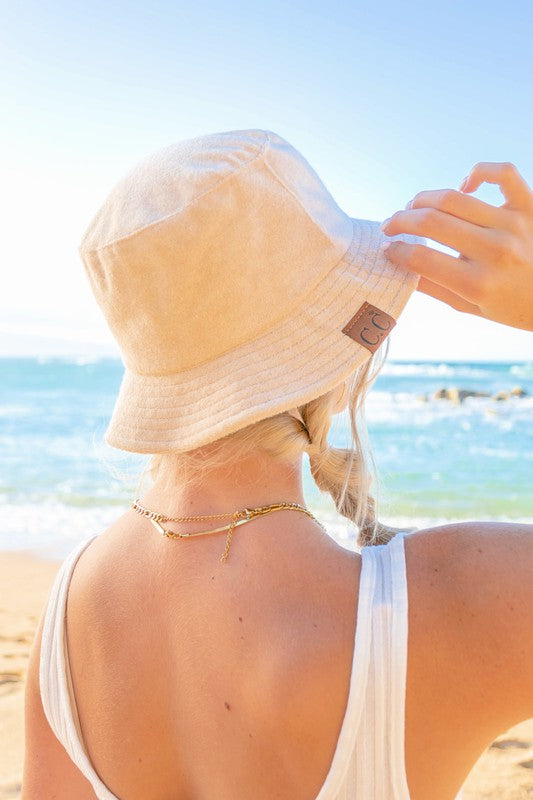 Woman wearing a CC Terry Cloth Bucket Hat and sunglasses at the beach.