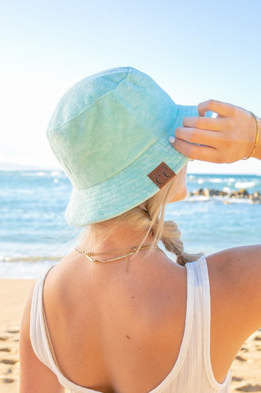 Woman wearing a CC Terry Cloth Bucket Hat and sunglasses at the beach.