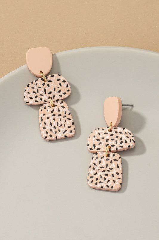 A pair of Flower Pattern Printed Acrylic Drop Earrings, featuring a lightweight pink design with geometric shapes and floral cutouts, displayed on a gray surface.