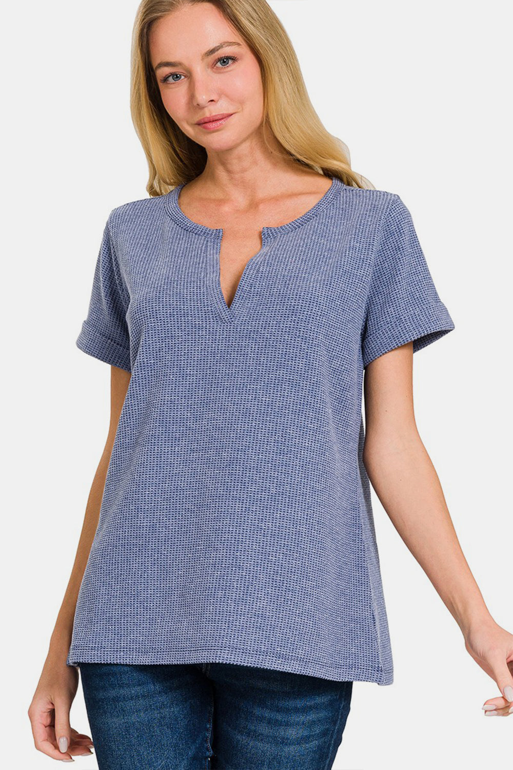 A person wearing a Zenana Notched Short Sleeve Waffle T-Shirt in blue and jeans stands against a plain background, capturing the essence of a casual wardrobe.