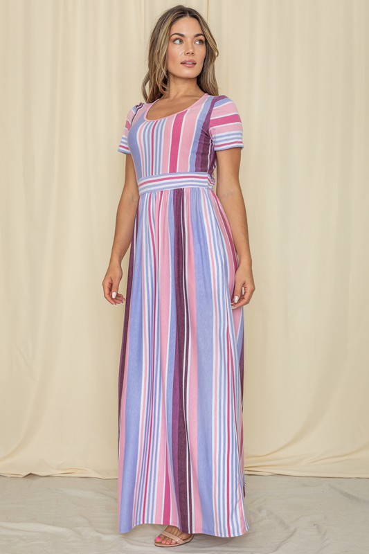 A person wearing a Short Sleeve Mix Stripe Maxi Dress featuring a long skirt with pockets stands against a beige backdrop. Made in the USA, this elegant dress effortlessly combines style and comfort.