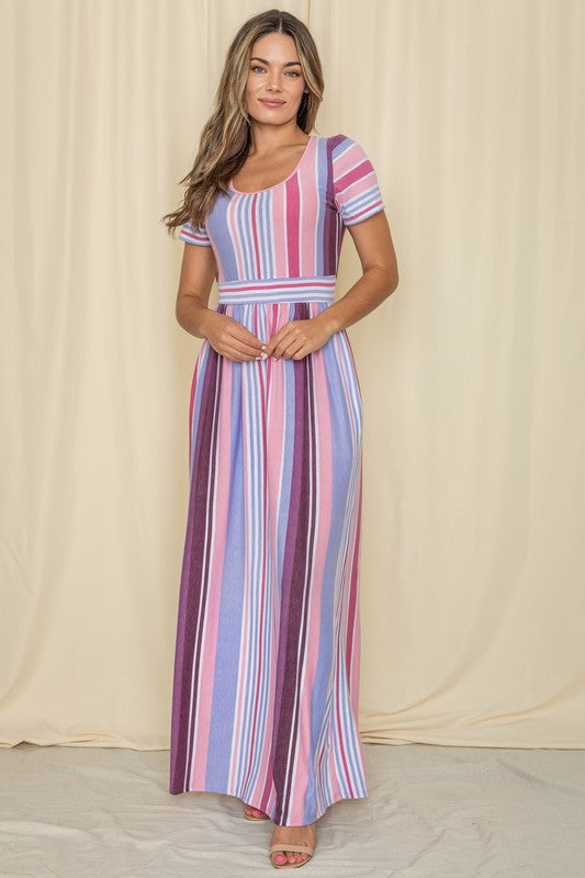 A person wearing a Short Sleeve Mix Stripe Maxi Dress featuring a long skirt with pockets stands against a beige backdrop. Made in the USA, this elegant dress effortlessly combines style and comfort.