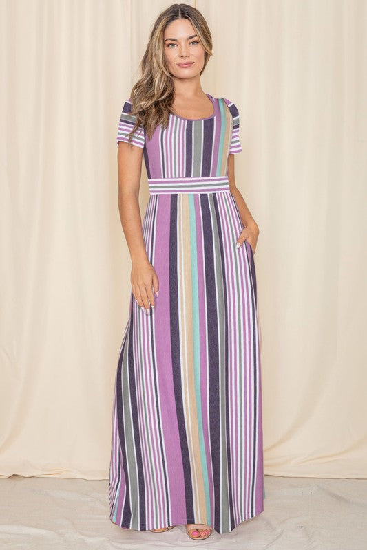 A person wearing a Short Sleeve Mix Stripe Maxi Dress featuring a long skirt with pockets stands against a beige backdrop. Made in the USA, this elegant dress effortlessly combines style and comfort.