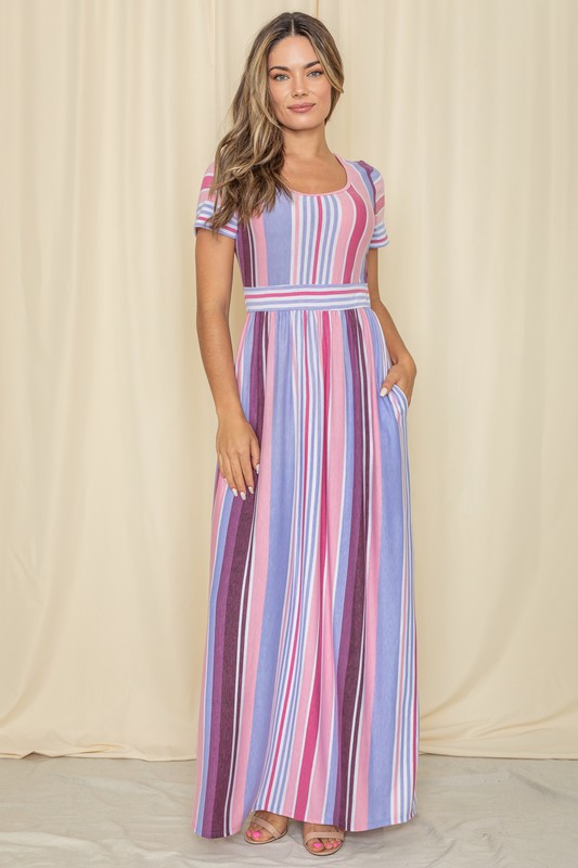 A person wearing a Short Sleeve Mix Stripe Maxi Dress featuring a long skirt with pockets stands against a beige backdrop. Made in the USA, this elegant dress effortlessly combines style and comfort.