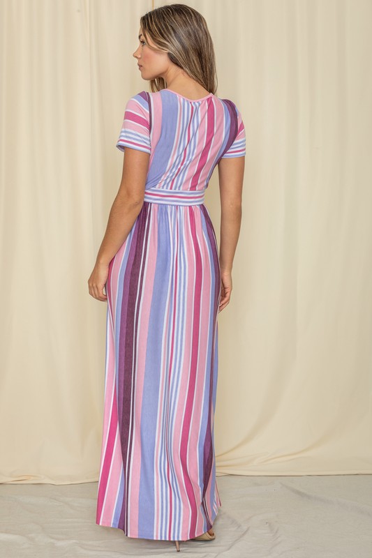 A person wearing a Short Sleeve Mix Stripe Maxi Dress featuring a long skirt with pockets stands against a beige backdrop. Made in the USA, this elegant dress effortlessly combines style and comfort.