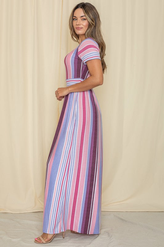 A person wearing a Short Sleeve Mix Stripe Maxi Dress featuring a long skirt with pockets stands against a beige backdrop. Made in the USA, this elegant dress effortlessly combines style and comfort.