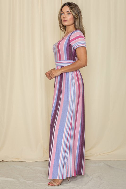 A person wearing a Short Sleeve Mix Stripe Maxi Dress featuring a long skirt with pockets stands against a beige backdrop. Made in the USA, this elegant dress effortlessly combines style and comfort.