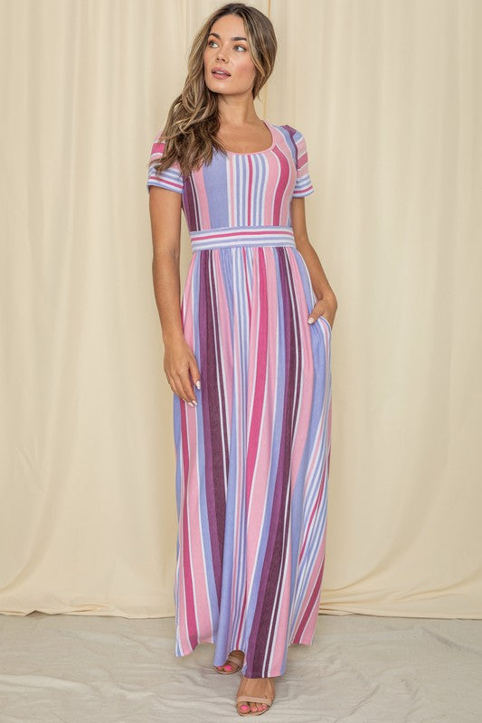 A person wearing a Short Sleeve Mix Stripe Maxi Dress featuring a long skirt with pockets stands against a beige backdrop. Made in the USA, this elegant dress effortlessly combines style and comfort.