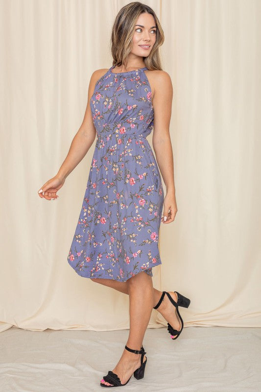 A woman stands gracefully against a light-colored background, modeling the Floral Halter Top Midi Dress, beautifully crafted in the United States.