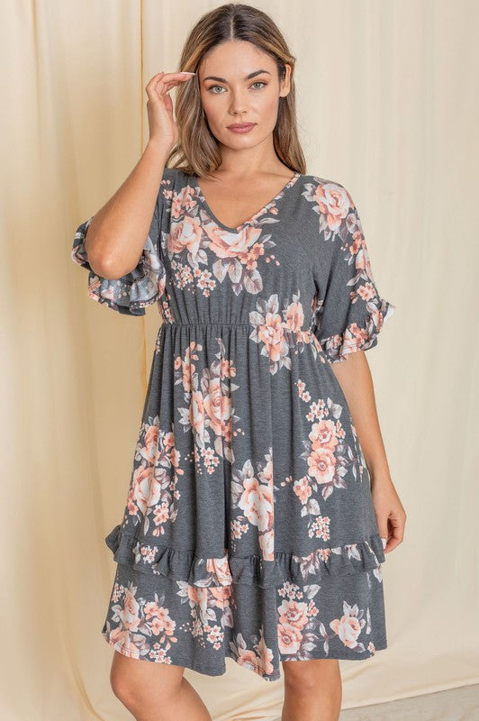 A woman wearing a Floral V Neck Ruffle Dress stands indoors, posing with one hand on her hip.