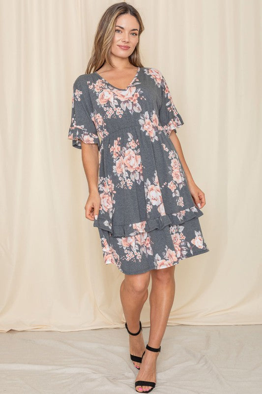 A woman wearing a Floral V Neck Ruffle Dress stands indoors, posing with one hand on her hip.