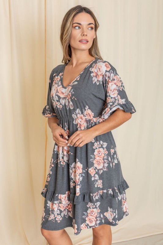 A woman wearing a Floral V Neck Ruffle Dress stands indoors, posing with one hand on her hip.