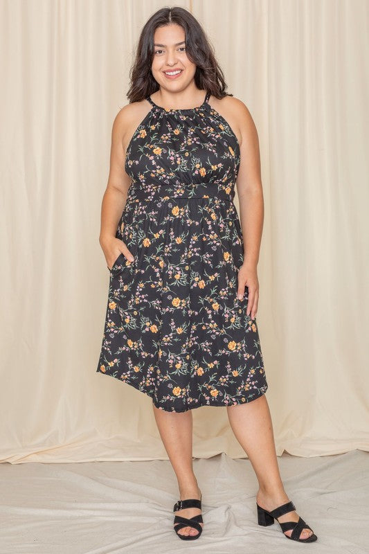 Wearing the elegant Plus Floral Halter Top Midi Dress, a person stands in front of a beige curtain, smiling with eyes closed. Crafted with care, this stunning piece is proudly made in the United States.