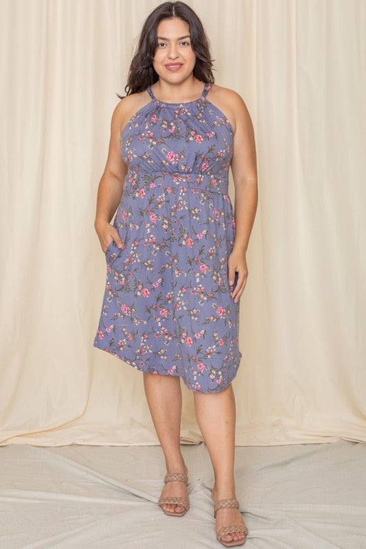 Wearing the elegant Plus Floral Halter Top Midi Dress, a person stands in front of a beige curtain, smiling with eyes closed. Crafted with care, this stunning piece is proudly made in the United States.