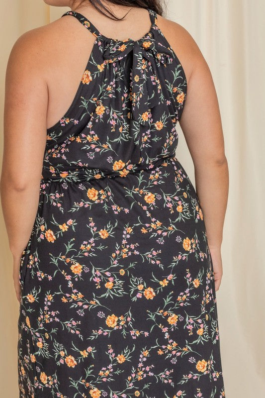 Wearing the elegant Plus Floral Halter Top Midi Dress, a person stands in front of a beige curtain, smiling with eyes closed. Crafted with care, this stunning piece is proudly made in the United States.