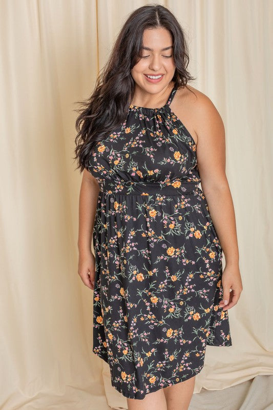 Wearing the elegant Plus Floral Halter Top Midi Dress, a person stands in front of a beige curtain, smiling with eyes closed. Crafted with care, this stunning piece is proudly made in the United States.