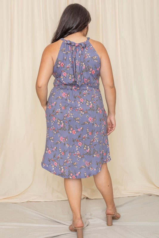 Wearing the elegant Plus Floral Halter Top Midi Dress, a person stands in front of a beige curtain, smiling with eyes closed. Crafted with care, this stunning piece is proudly made in the United States.