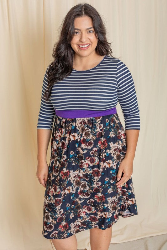 A woman wearing a Floral Band Midi Dress grins joyfully while standing in front of a beige curtain.