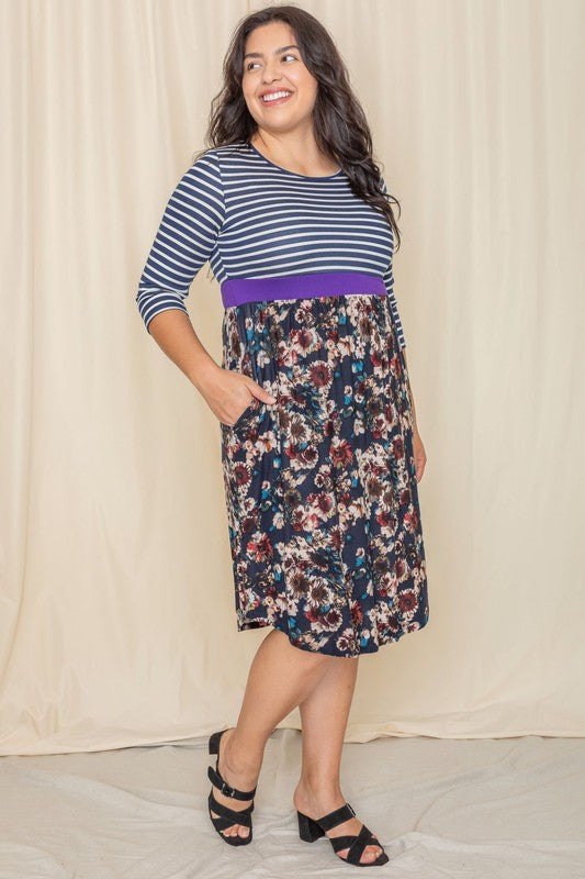 A woman wearing a Floral Band Midi Dress grins joyfully while standing in front of a beige curtain.