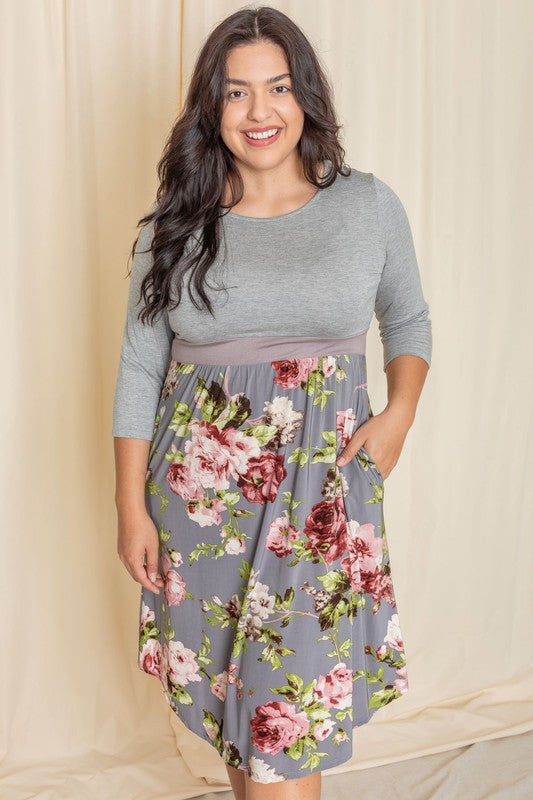 A woman wearing a Floral Band Midi Dress grins joyfully while standing in front of a beige curtain.