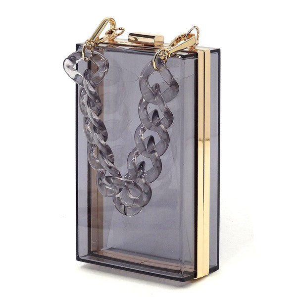 The Acrylic Chain Handle See Thru Crossbody Clutch is a rectangular pink acrylic crossbody clutch that features a sleek gold chain strap and a detachable shoulder chain, highlighted by an elegant pink acrylic chain handle.