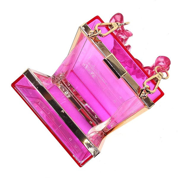 The Acrylic Chain Handle See Thru Crossbody Clutch is a rectangular pink acrylic crossbody clutch that features a sleek gold chain strap and a detachable shoulder chain, highlighted by an elegant pink acrylic chain handle.