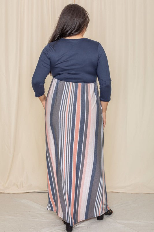 A person wearing the Plus Stripe Quarter Sleeve Maxi Dress, which showcases a navy top and a vertical striped skirt in blue, gray, and coral hues, stands in front of a beige curtain.