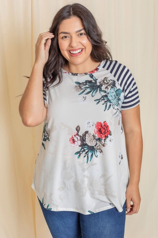 Wearing a Plus stripe sleeve floral top/tunic, a person smiles against a light background.