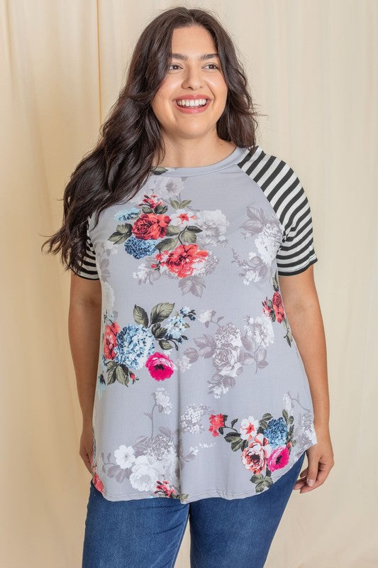 Wearing a Plus stripe sleeve floral top/tunic, a person smiles against a light background.