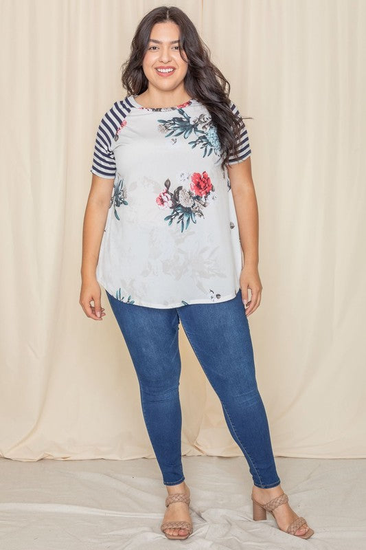 Wearing a Plus stripe sleeve floral top/tunic, a person smiles against a light background.