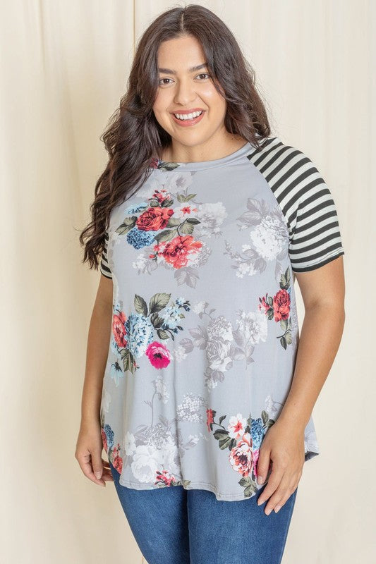 Wearing a Plus stripe sleeve floral top/tunic, a person smiles against a light background.