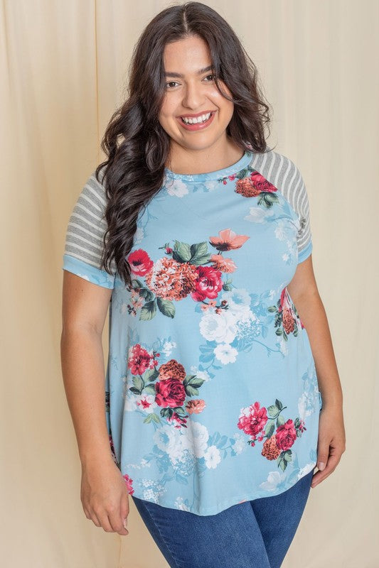 Wearing a Plus stripe sleeve floral top/tunic, a person smiles against a light background.