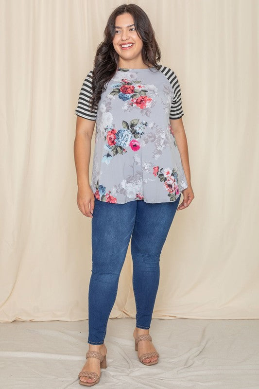 Wearing a Plus stripe sleeve floral top/tunic, a person smiles against a light background.