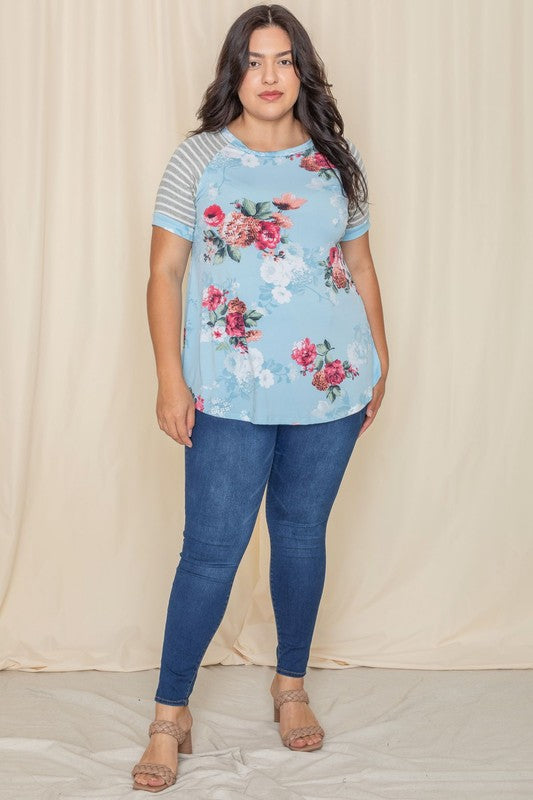 Wearing a Plus stripe sleeve floral top/tunic, a person smiles against a light background.