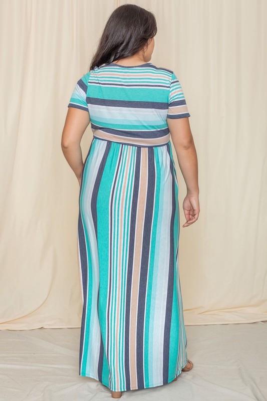 A person elegantly stands in front of a light-colored curtain, wearing the Plus Short Sleeve Stripe Maxi Dress in hues of blue, gray, and white.