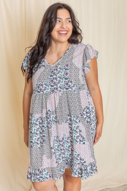 A person wearing the Plus Mix Floral Flutter Sleeve Mini Dress poses gracefully with one hand holding the dress's hem, standing against a neutral background.