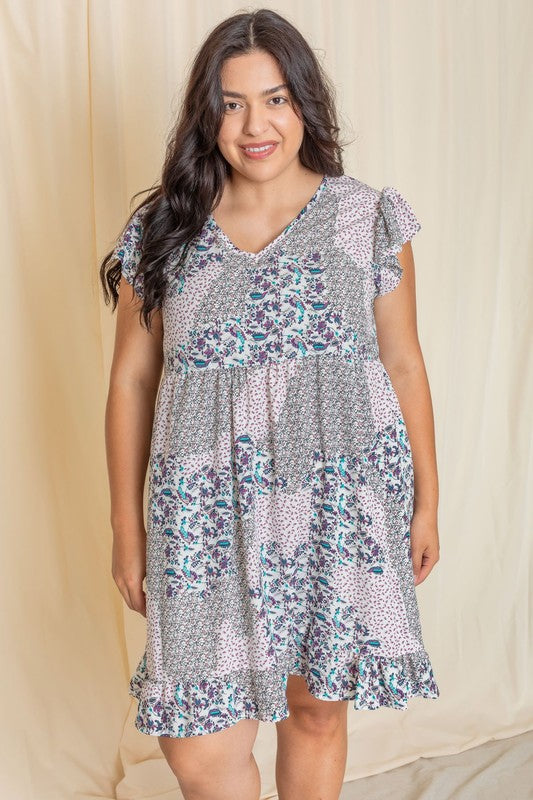 A person wearing the Plus Mix Floral Flutter Sleeve Mini Dress poses gracefully with one hand holding the dress's hem, standing against a neutral background.