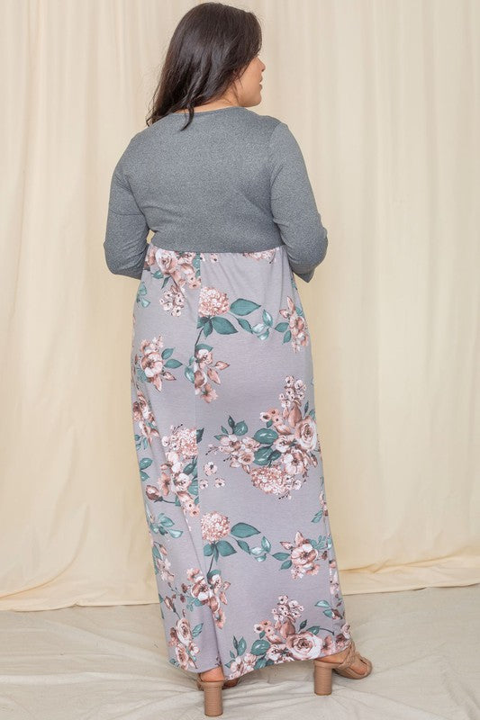 A person stands against a beige background wearing the Plus Quarter Sleeve Floral Maxi Dress, featuring a gray top with floral designs, proudly made in the United States.