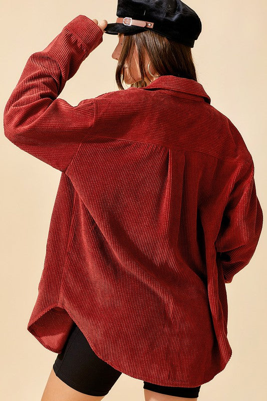 A person wearing a pink Chaser Madera Cozy Button Down Shacket, black pants, and a beige hat stands against a pastel-colored background, showcasing a casual chic look.