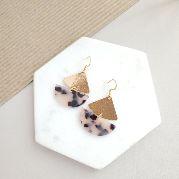 The Ava Blonde Tortoise earrings showcase geometric designs in blonde tortoise with gold-plated hooks, tastefully arranged on a marble hexagonal tray.