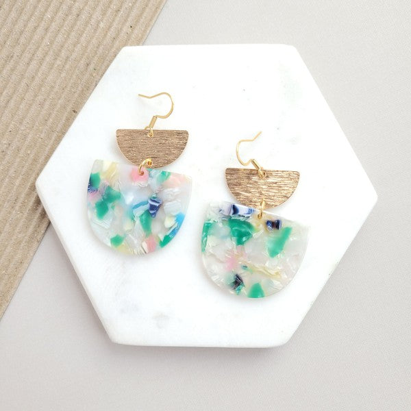 The Harper Spring Fling earrings boast colorful resin and gold-plated hooks, highlighting geometric elegance against a hexagonal white marble background. Crafted from plant-based acetate acrylic, these earrings offer a stylish and eco-friendly option.