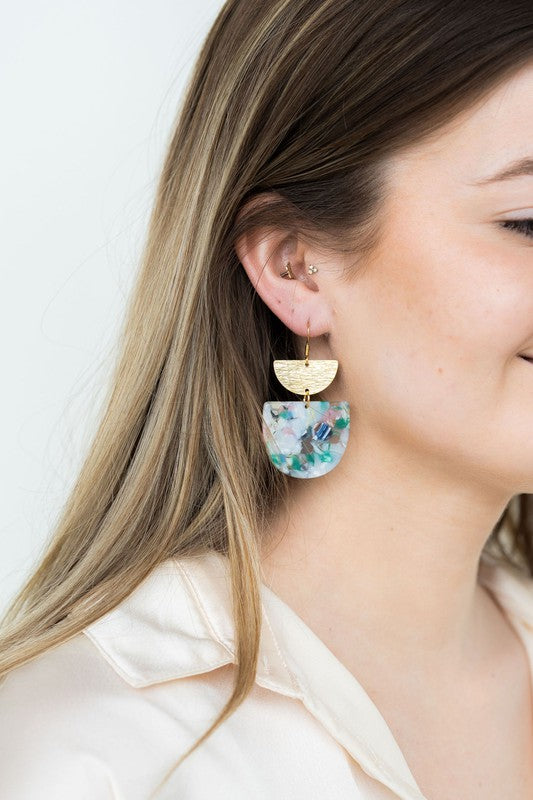 The Harper Spring Fling earrings boast colorful resin and gold-plated hooks, highlighting geometric elegance against a hexagonal white marble background. Crafted from plant-based acetate acrylic, these earrings offer a stylish and eco-friendly option.