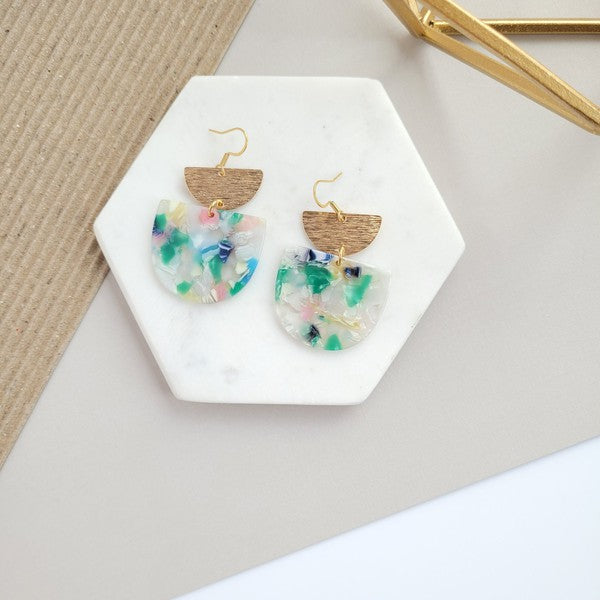 The Harper Spring Fling earrings boast colorful resin and gold-plated hooks, highlighting geometric elegance against a hexagonal white marble background. Crafted from plant-based acetate acrylic, these earrings offer a stylish and eco-friendly option.