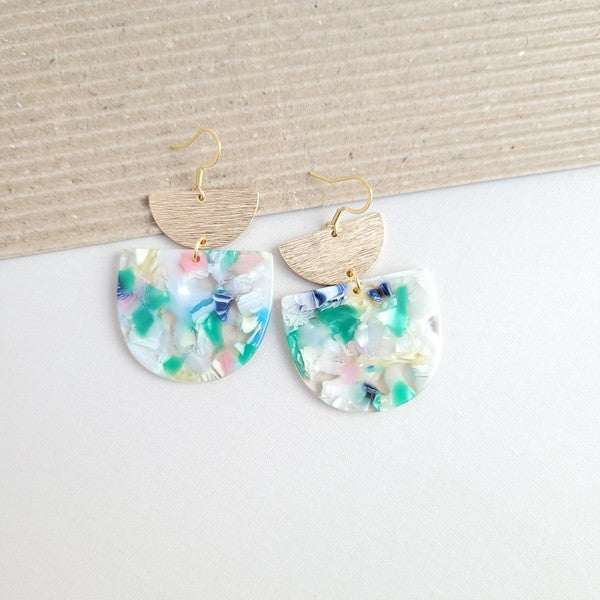 The Harper Spring Fling earrings boast colorful resin and gold-plated hooks, highlighting geometric elegance against a hexagonal white marble background. Crafted from plant-based acetate acrylic, these earrings offer a stylish and eco-friendly option.