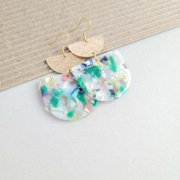 The Harper Spring Fling earrings boast colorful resin and gold-plated hooks, highlighting geometric elegance against a hexagonal white marble background. Crafted from plant-based acetate acrylic, these earrings offer a stylish and eco-friendly option.