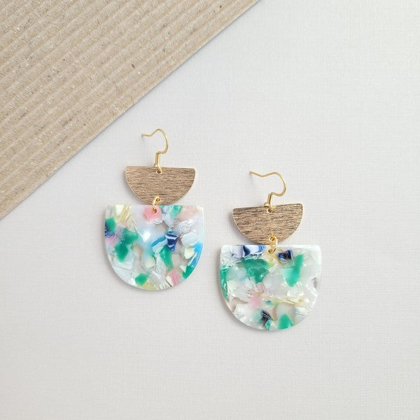 The Harper Spring Fling earrings boast colorful resin and gold-plated hooks, highlighting geometric elegance against a hexagonal white marble background. Crafted from plant-based acetate acrylic, these earrings offer a stylish and eco-friendly option.