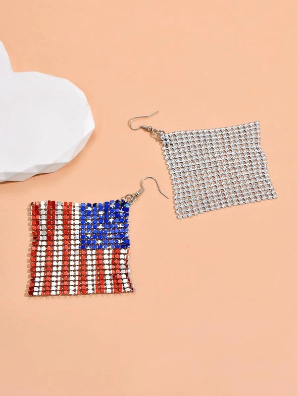 The Stars and Stripes earrings feature a lightweight aluminum design with an American flag motif set against a soft peach background.