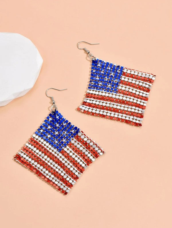 The Stars and Stripes earrings feature a lightweight aluminum design with an American flag motif set against a soft peach background.