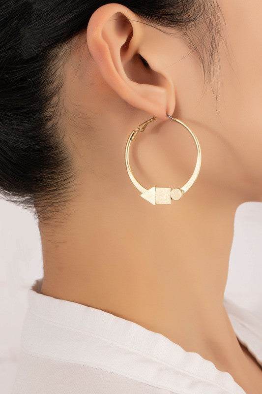 Two flat hoop earrings with intricate designs from the Geo shapes collection rest on a smooth, light surface.